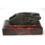 A desk ornament modelled as a WWI tank, mounted on a wooden base with Tank Corps badge and medals.