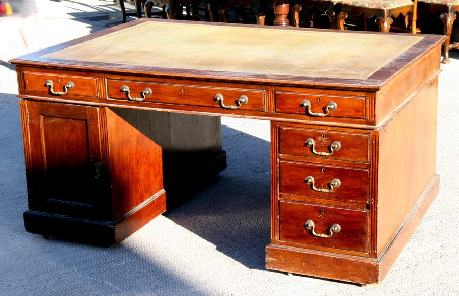 An early 20th century oak twin pedestal partner's desk, the top with green inset leather top,