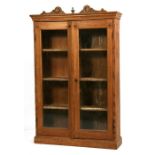 A stripped pine glazed wall cabinet, the two doors enclosing a shelved interior, 69cms (27ins)