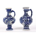 A near pair of continental stoneware jugs decorated with flowers and foliate scrolls in a crest, the
