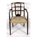 An Edwardian walnut elbow chair with needlepoint upholstered seat, on square tapering legs.