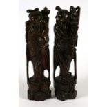 A pair of Chinese rootwood figures inlaid with silver wire decoration, 29cms (11.5ins) high.