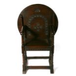 An early 20th century oak monk's chair with carved circular tilt-top, 68.5cms (27ins) wide overall.