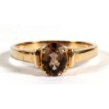 A yellow metal dress ring set with a single oval smokey quartz, approx UK size 'S'.