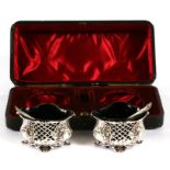 A pair of Victorian pierced silver salts with blue glass liners and matching spoons, cased,