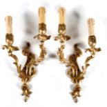 A pair of twin-arm gilt brass wall lights, 41cms (16ins) high.