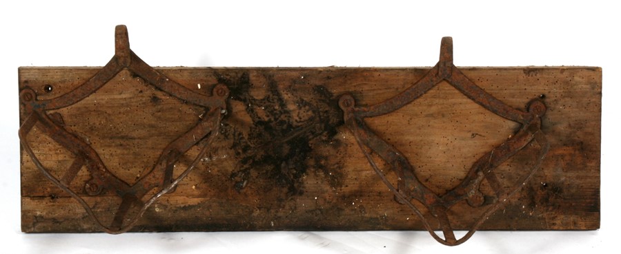 A pair of cast saddle racks mounted on a wooden backboard.