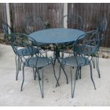 A circular green painted metal garden table and six chairs.