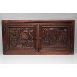 A Chinese hardwood scholars cabinet with carved figural panels, 42cms (16.5ins) wide.