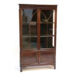 An Edwardian mahogany display cabinet, the pair of glazed doors enclosing a shelved interior above a