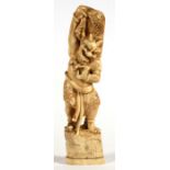 A late 19th century Japanese carved ivory figure depicting an Oni standing on a boulder and carrying