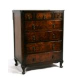A figured walnut chest with three short above four long graduated drawers, on dwarf cabriole feet,