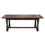 An oak extending refectory dining table on gun barrel turned legs joined by a stretcher, 213cms (