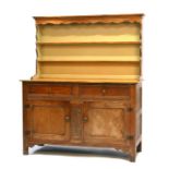 An oak dresser, the shaped plate rack with two shelves above two frieze drawers with cupboards