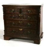 An oak chest of two short and three long graduated drawers, with carved figural pilasters and