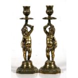 A pair of 19th century bronze cherub candlesticks, 28cms (11ins) high.