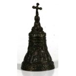 A cast bronze hand bell decorated with figures and surmounted with a cross, 19cms (7.5ins) high.
