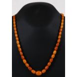 A graduated oval butterscotch amber bead necklace, the largest bead 15mm wide.