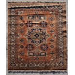 A Persian rug decorated with a geometric design within a foliate border, on a burnt orange ground,