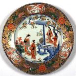 A large 19th century Japanese Imari charger decorated with figures on a terrace within a foliate