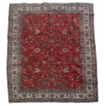 A Persian Tabriz handmade woollen carpet with floral design, on a red ground, 342 by 236cms (134