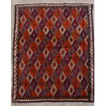 A Persian Baluch woollen handmade rug with repeated geometric design on a burnt red ground, 225 by