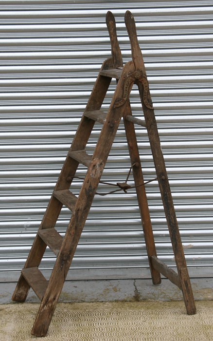 A Victorian Simplex seven-tread pine folding step ladder with shaped iron hinges and iron cross