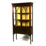 An Edwardian inlaid mahogany display cabinet, the pair of glazed doors enclosing a shelved interior,