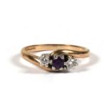 A 9ct gold ring set with a central amethyst flanked by diamonds, approx UK size 'K'.