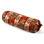 A bolster cushion decorated with flowers on a red ground, 103cms (40.5ins) wide.