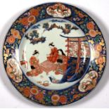 A large 19th century Japanese Imari charger decorated with figures playing a board game within a