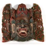 A Thai carved and painted wooden mask, 56cms (22ins) wide.
