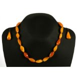 A butterscotch amber bead necklace; together with matching drop earrings, total weight 20g.