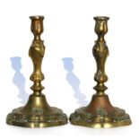 A pair of 18th century bronze candlesticks with armorial crest, 24cms (9.5ins) high.
