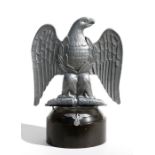 A German cast aluminium eagle on a turned wooden plinth, overall 32cms (12.5ins) high.