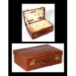 An early 20th century fitted leather case containing ivory backed brushes and hand mirror, 60cms (