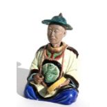 A 19th century pottery nodding figure in the form of a seated man holding a cymbal, 16cms (6.