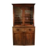 A 19th century mahogany bookcase on cupboard, the pair of glazed doors enclosing a shelved interior,