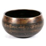 A Tibetan bronze singing bowl with Sanskrit character around the rim, 11.5cm (4.5ins) diameter.