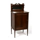 An Edwardian mahogany bedside cabinet, the mirrored back above a panelled door, on square tapering