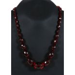 A cherry amber Bakelite like faceted graduated bead necklace, the largest bead 30mm wide.