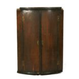 A 19th century oak bowfronted hanging corner cabinet with a shelved interior, 69cms (27ins) wide.