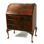 A figured walnut ladies bureau, the fall flap enclosing fitted interior with three long drawers