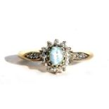 A 9ct gold diamond and aquamarine dress ring, the central aquamarine surrounded by diamonds, with