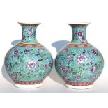 A pair of Chinese famille rose vases decorated with flowers on a turquoise ground, 30cms (12ins)
