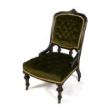 A Victorian ebonised nursing chair with upholstered seat and back, on turned front supports.