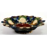 A 19th century majolica shallow footed bowl decorated in relief with masks and flowers, 23cms (9ins)