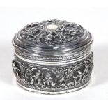 A Burmese white metal pot & cover highly decorated in relief with figures, 8cms (3ins) diameter.