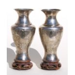 A pair of Japanese white metal vases on pierced hardwood stands, decorated with a hawk perched on