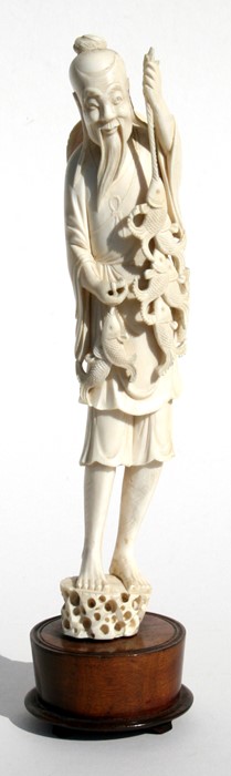 A late 19th / early 20th century Chinese carved ivory figure of a fisherman holding his catch, 28cms